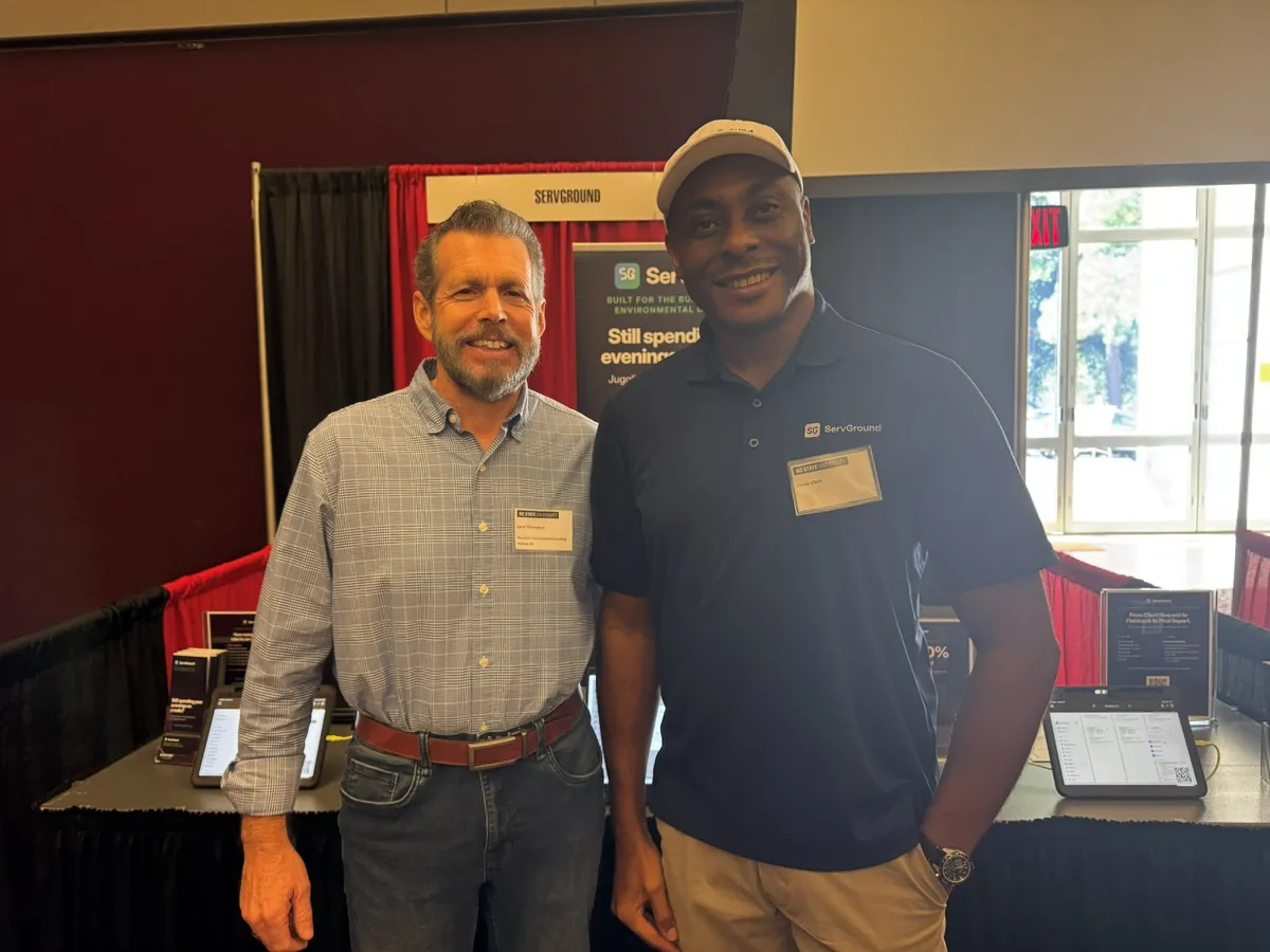 David Obim with a conference attendee in front of the ServGround booth banner