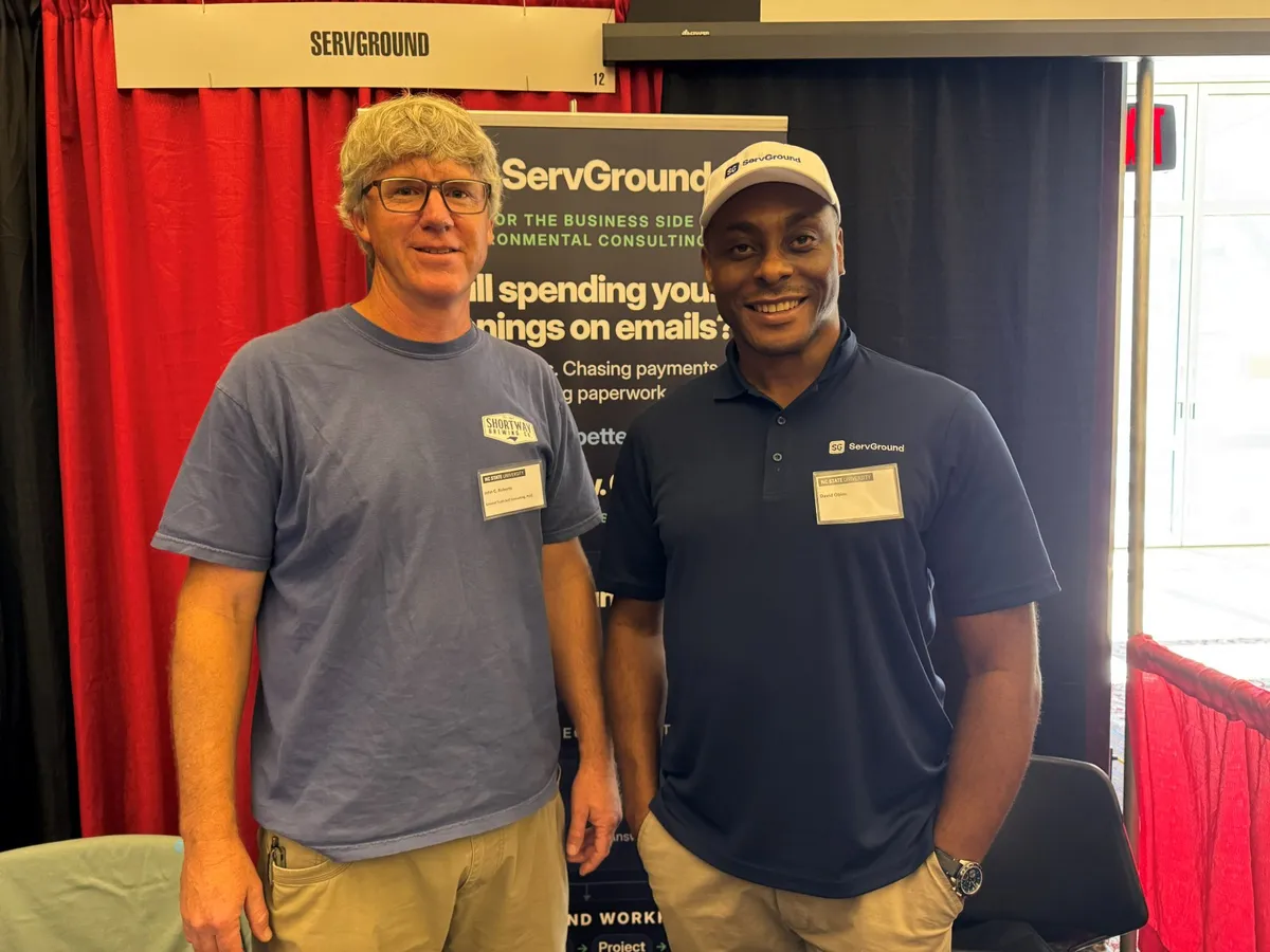 David Obim with a conference attendee from a soil consulting firm in front of the ServGround banner