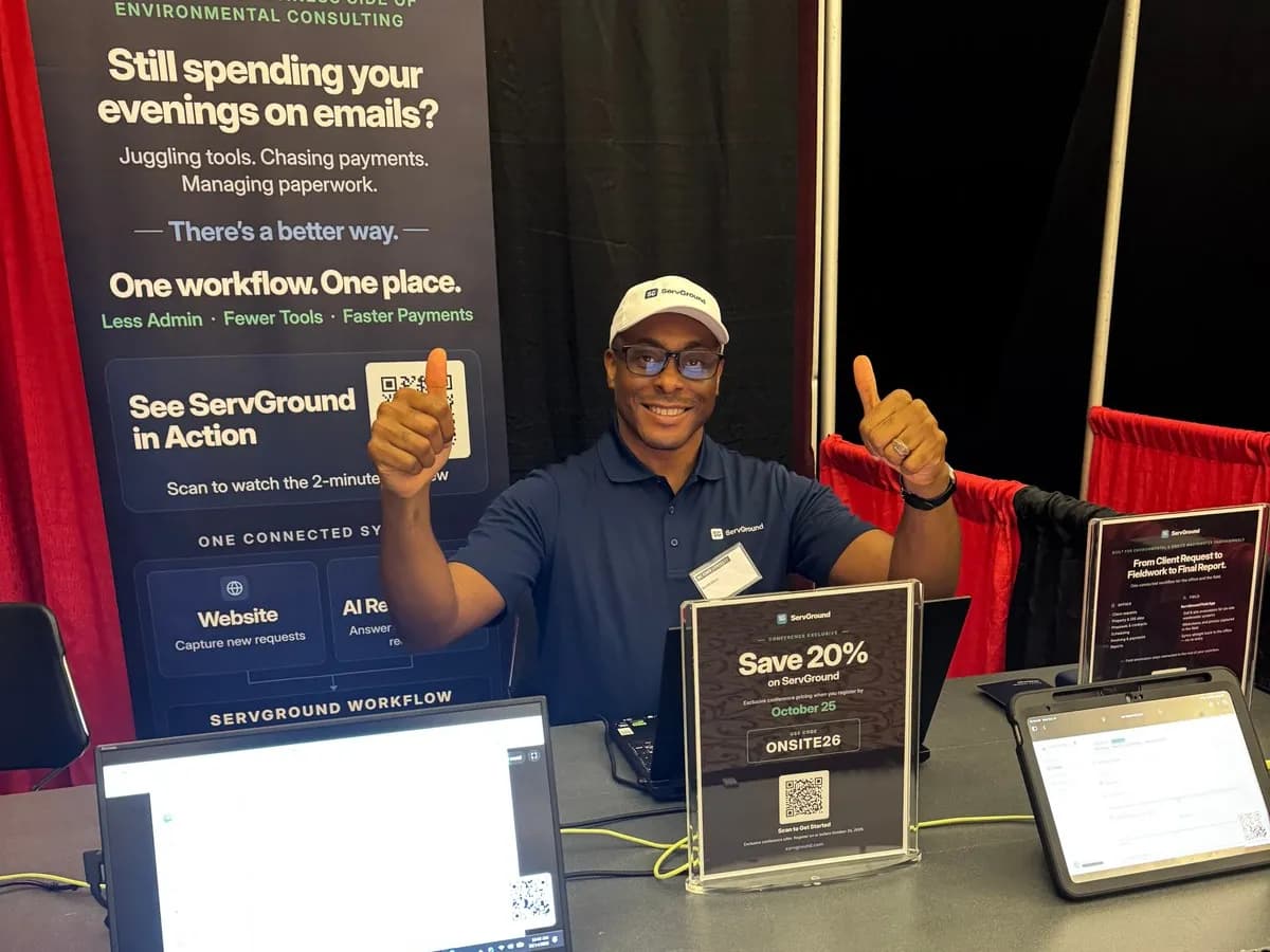 David Obim behind the ServGround booth table with a tablet and a conference offer sign