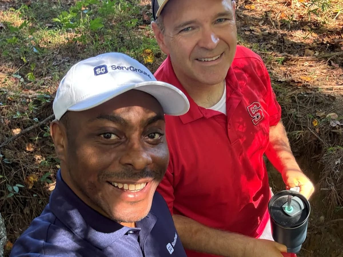 David Obim and a field professional next to an open soil pit